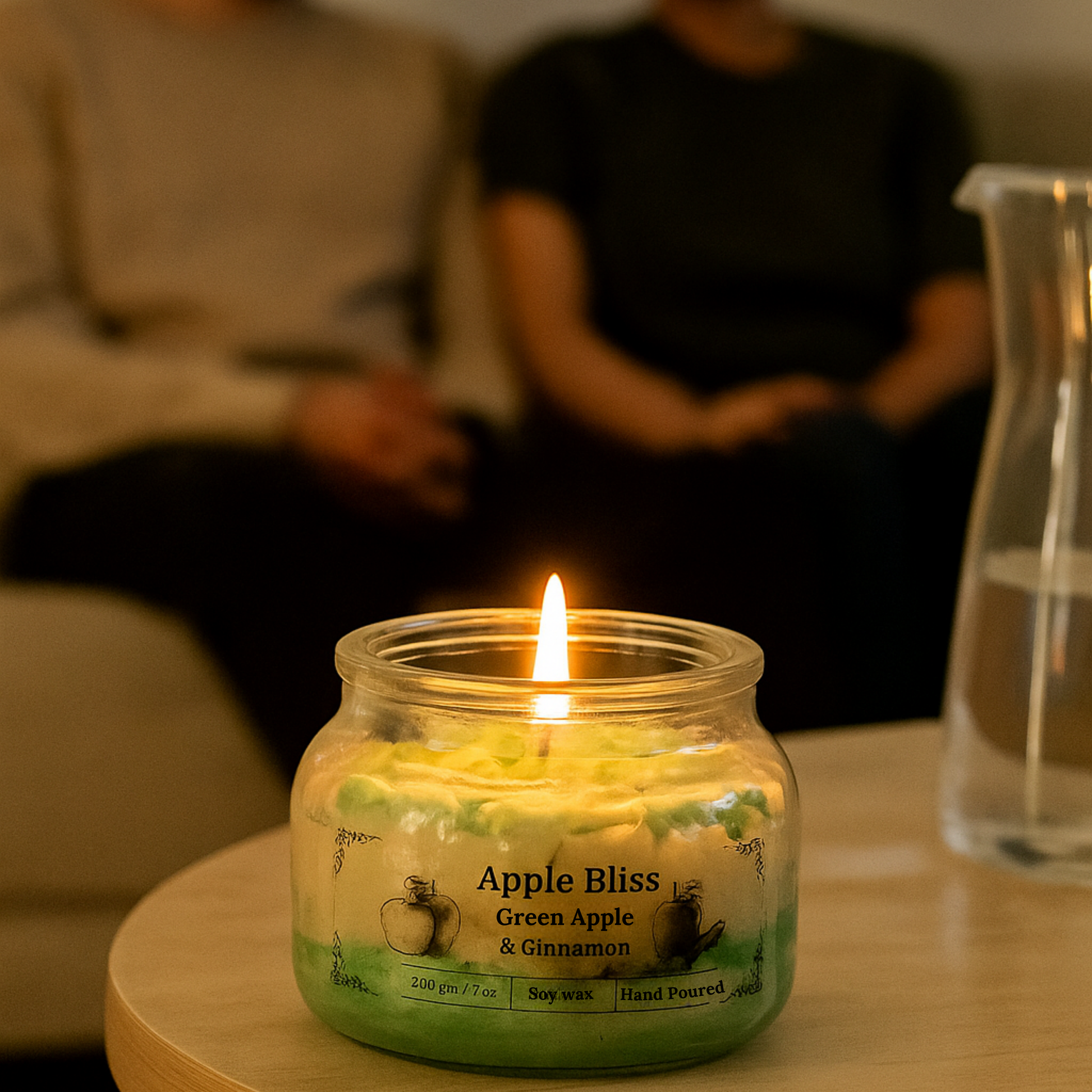 Eco friendly candle labeled 'Apple Bliss' on a table with blurred people in the background
