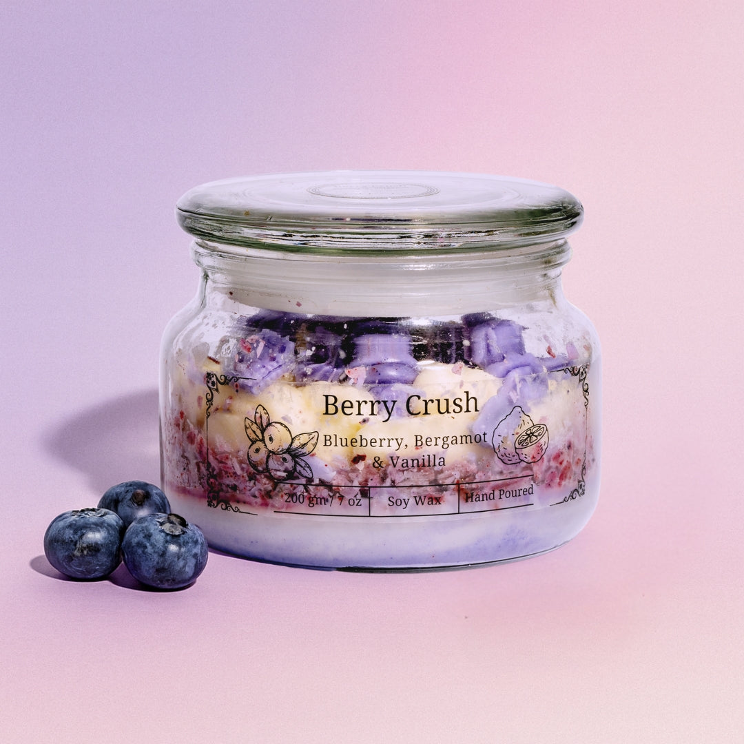 Jar of 'Berry Crush' eco friendly candle with blueberries on a pink background