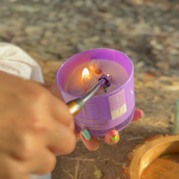 Eco friendly Hand lighting a purple candle with a match outdoors.