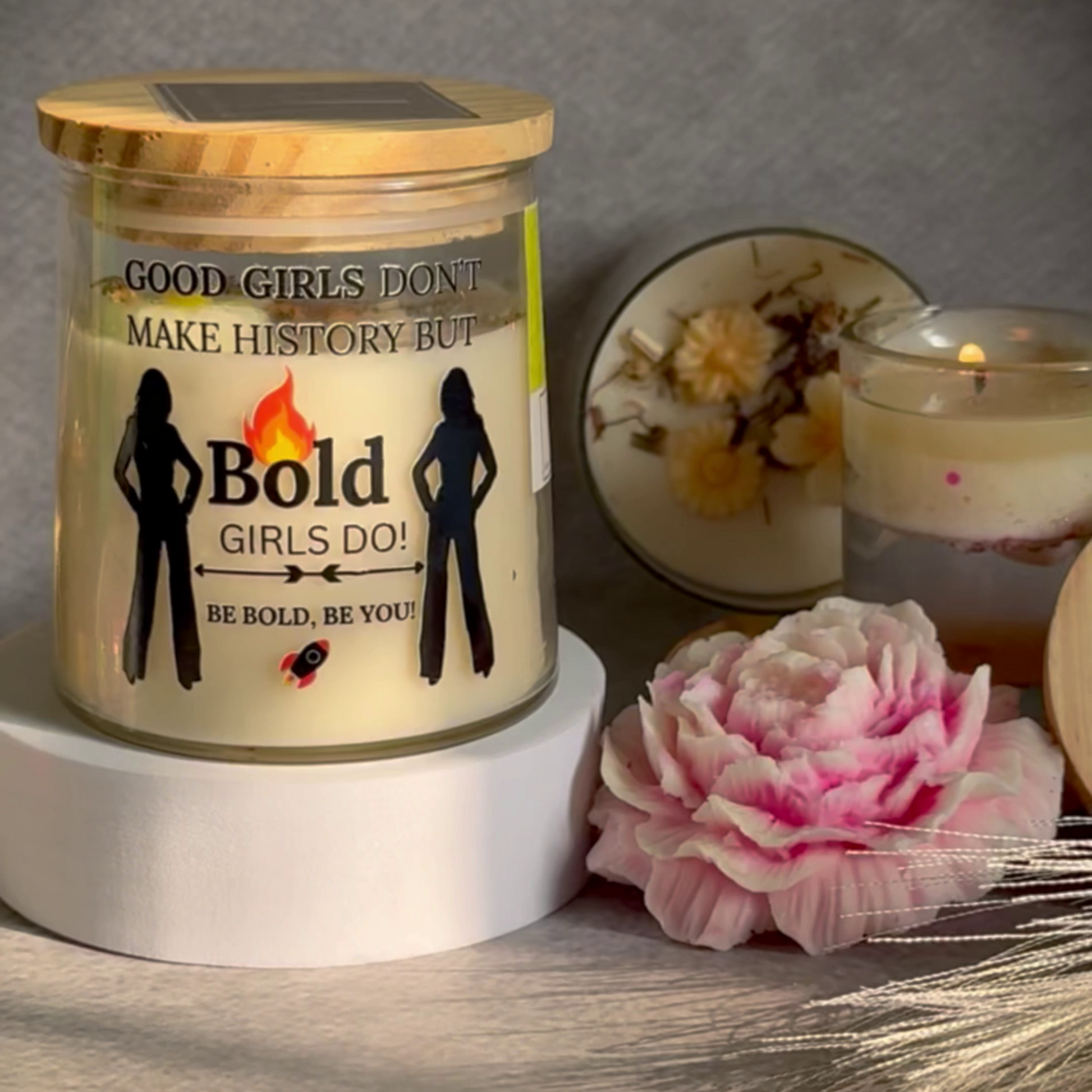 Eco conscious ecofriendly Candle jar with motivational message, solar panel, and pink flower on wooden surface