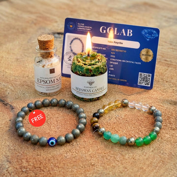 Two beaded bracelets on a wooden surface with a lit candle, bottle of Epsom salt, and GCLAB card in the background.