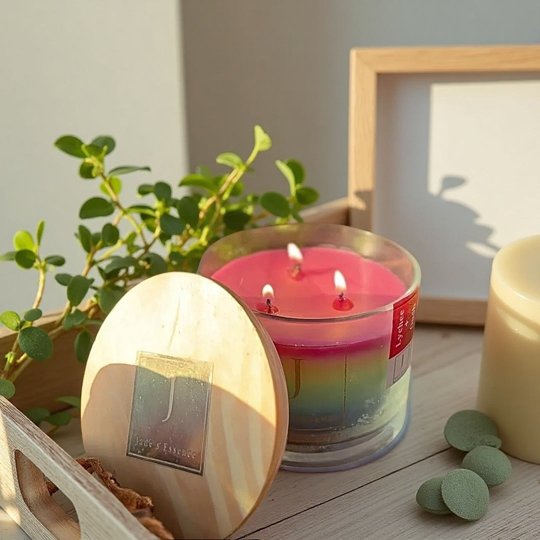Gay and LGBTQ friendly Ecofriendly  pride candle Lychee and Oudh fragranced from jade's essence  Candle with a rainbow design on a wooden surface with a plant and framed picture in the background.