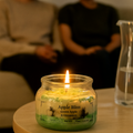 Eco friendly candle labeled 'Apple Bliss' on a table with blurred people in the background
