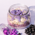 Jar of 'Berry Crush' Eco friendly candle with purple and white wax pieces on a light background.