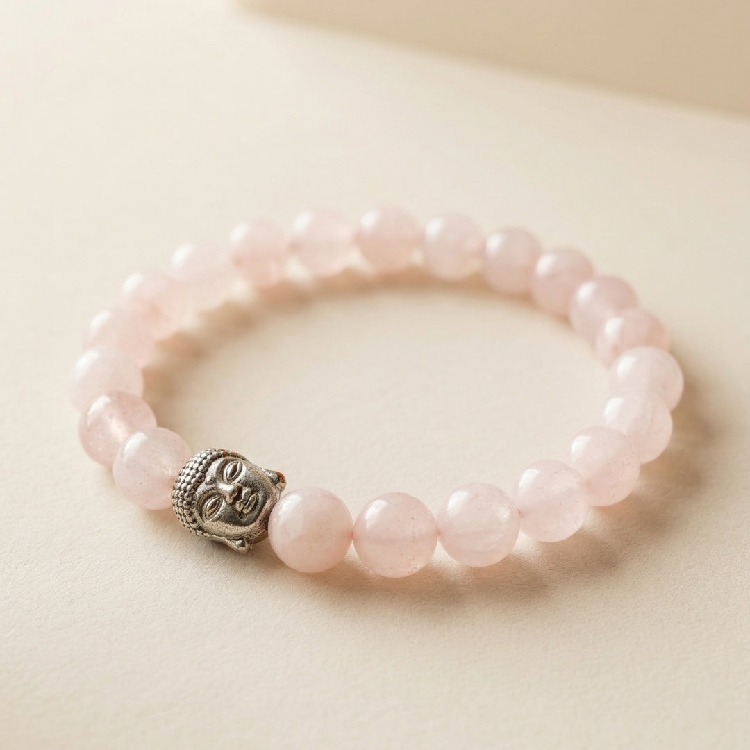 Pink beaded bracelet with a Buddha charm on a light beige background