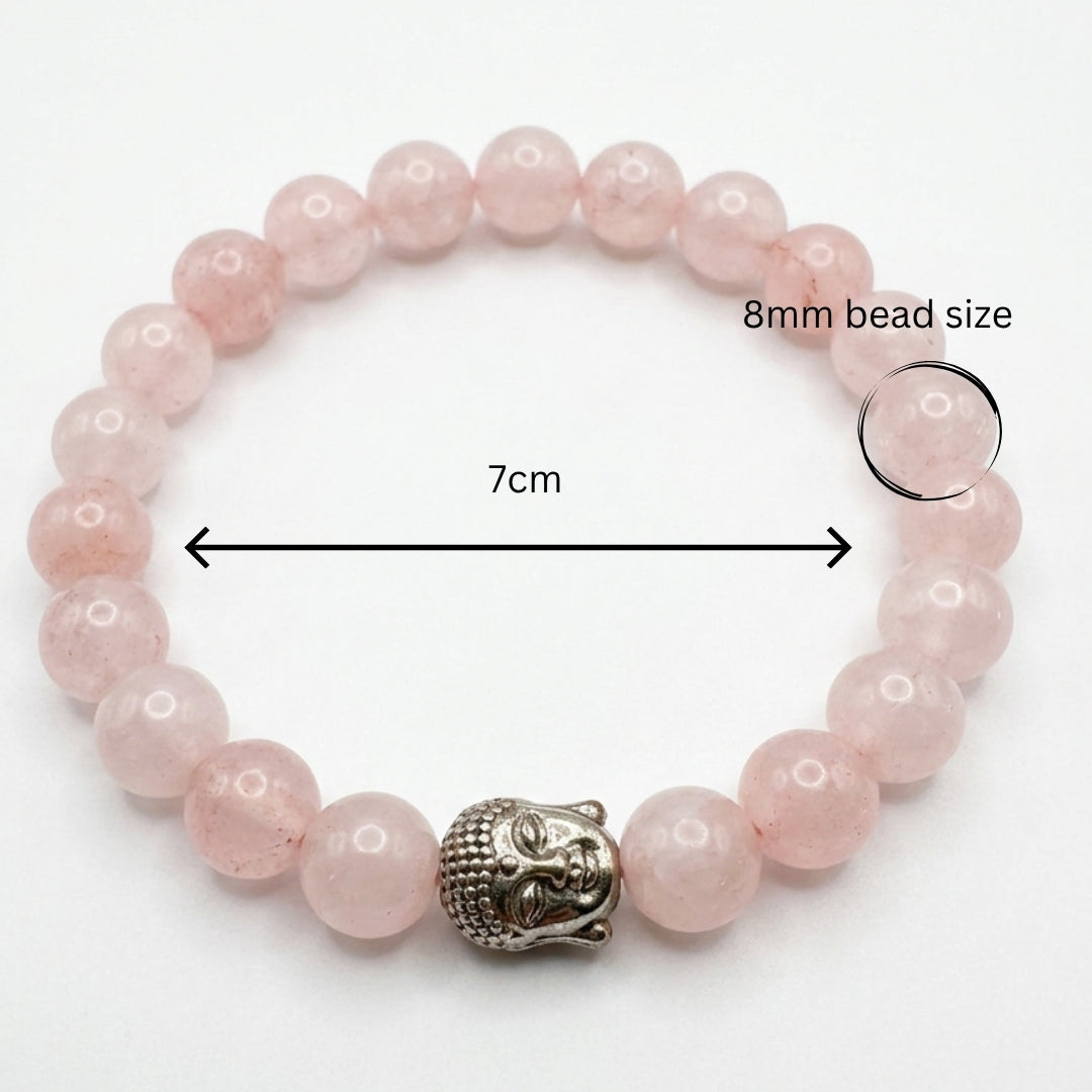 Pink beaded bracelet with a Buddha charm on a light beige background