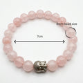 rose quartz bracelet with a Buddha head charm on a white background