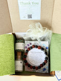Gift box with a bottle of Epsom salt, a bracelet, and a card inside.