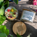 ecofriendly Candle with decorative elements and a label on a surface with plants around