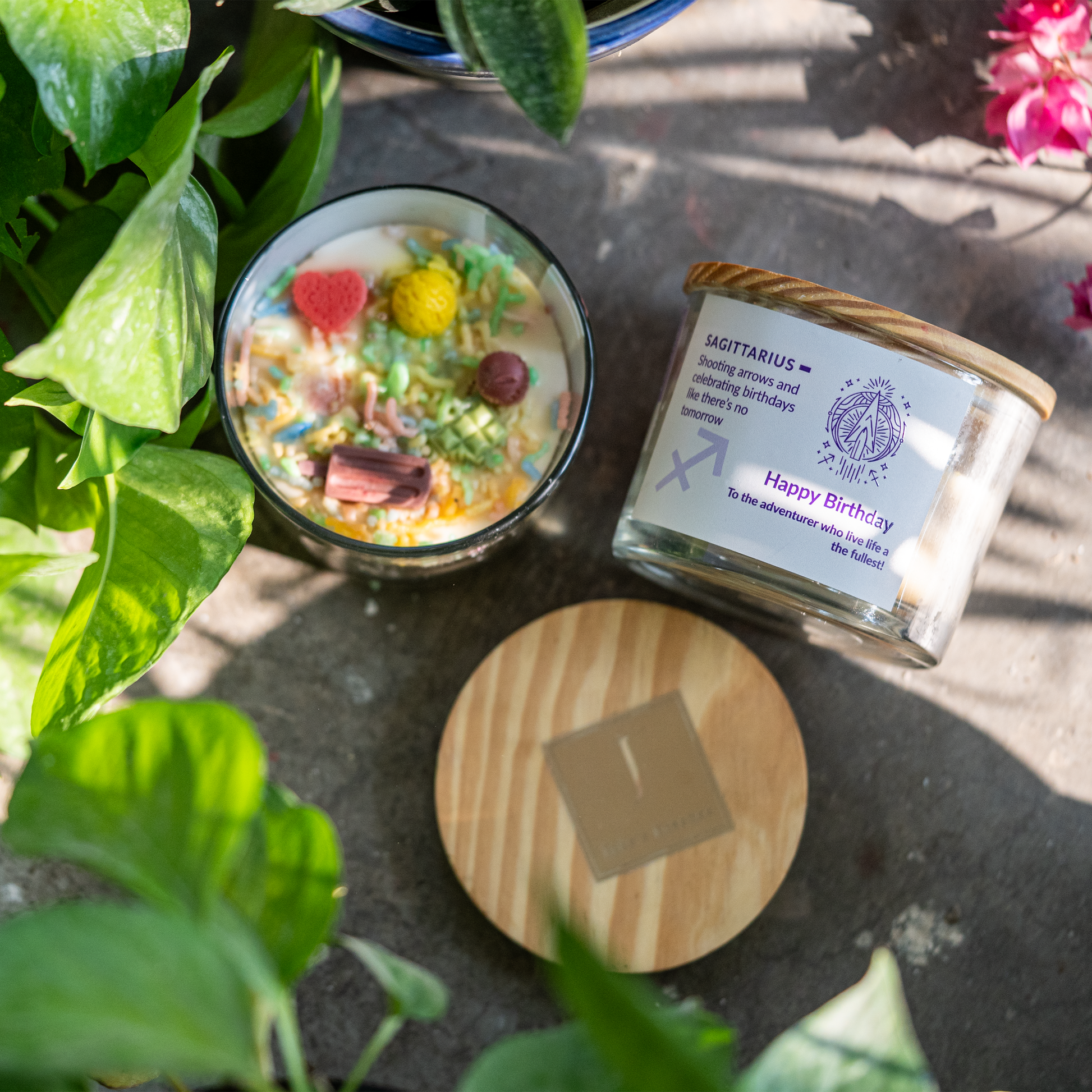 ecofriendly Candle with decorative stones and a wooden lid on a stone surface with plants around.
