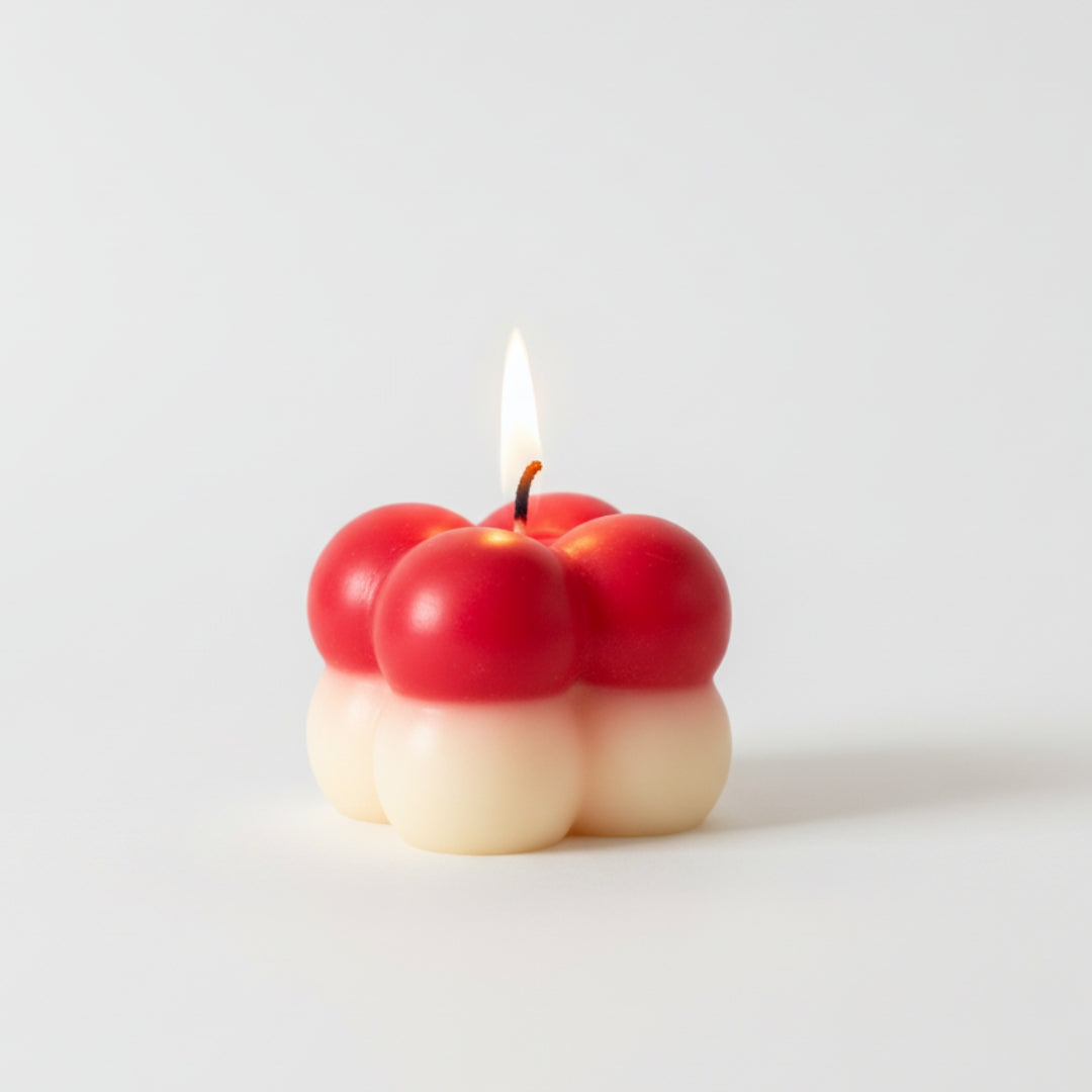 Candle shaped like a cluster of red apples on a white background