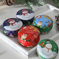 Set of Christmas-themed tins with snowmen, Santa Claus, and reindeer designs on a white tray.