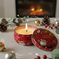 Candle in a red Christmas-themed tin with decorative elements on a table.