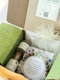 Open box containing wellness items including a bottle labeled 'Epsom', bracelet, and other packaging.