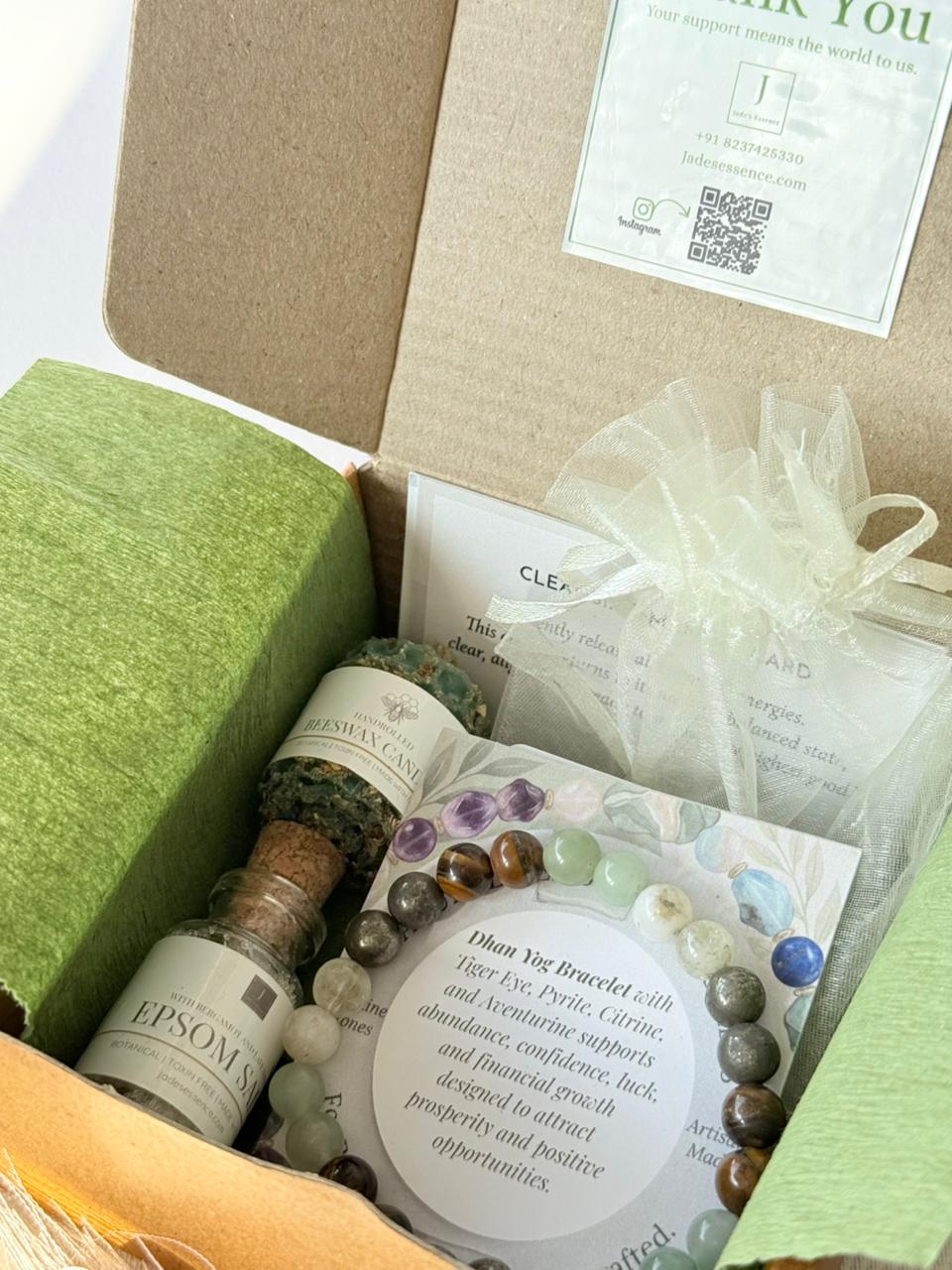 Open box containing wellness items including a bottle labeled 'Epsom', bracelet, and other packaging.