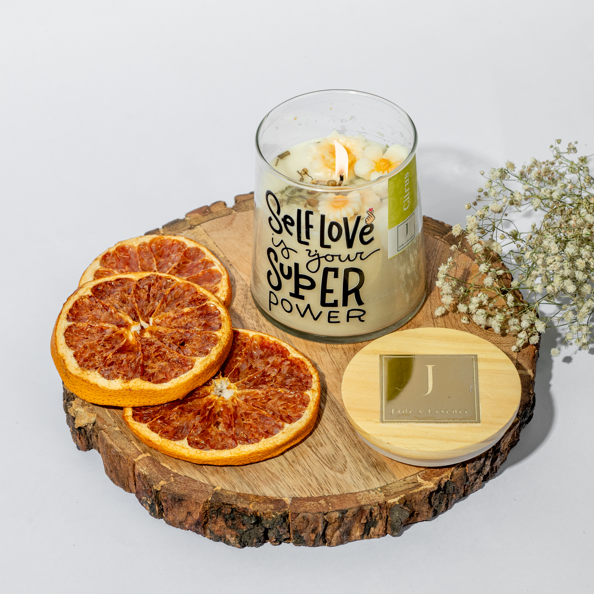eco friendly Candle with 'Self Love is your Super Power' text on a wooden board with dried oranges and flowers.