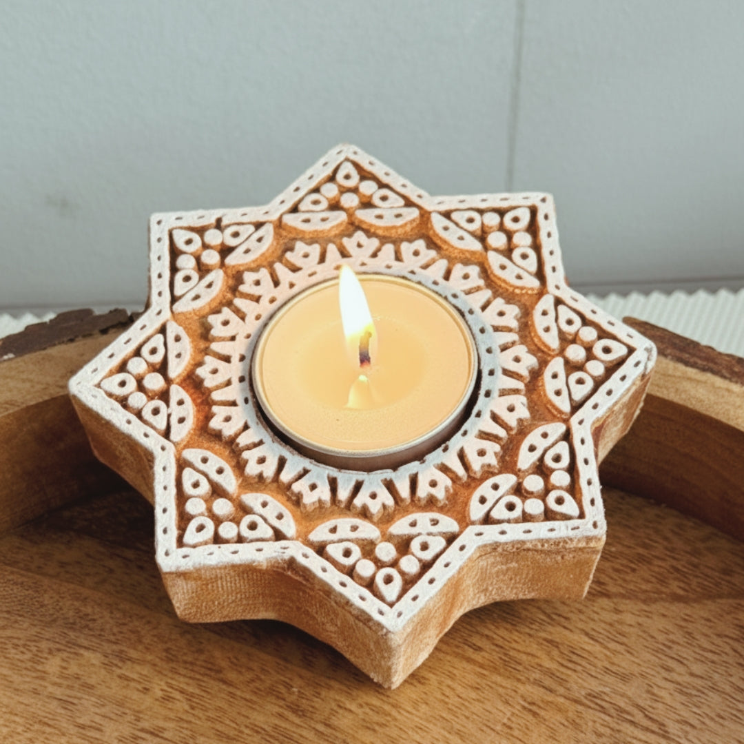 Decorative wooden candle holder with a lit candle on a wooden surface.