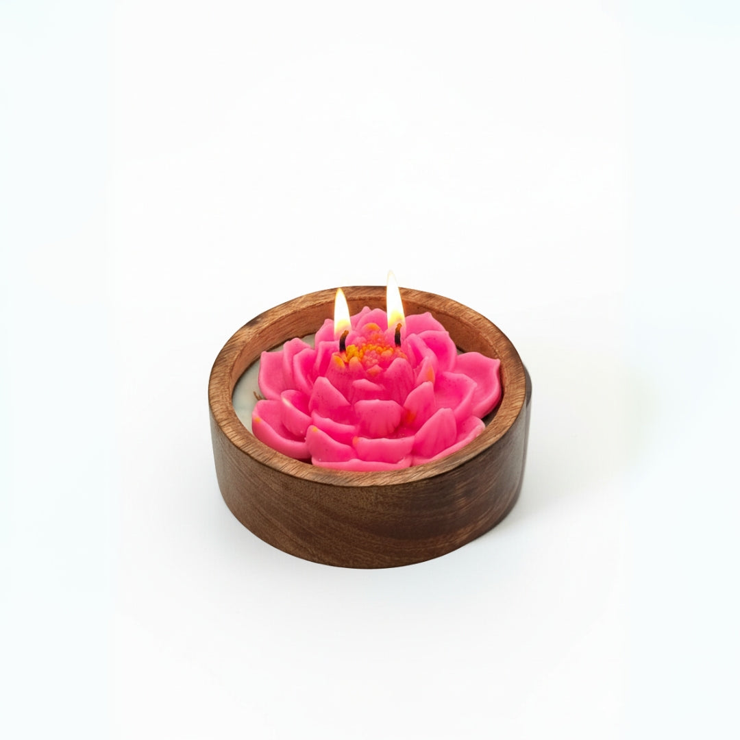 Pink flower-shaped candle in a wooden holder on a white background