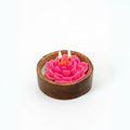 Pink flower-shaped candle in a wooden holder on a white background
